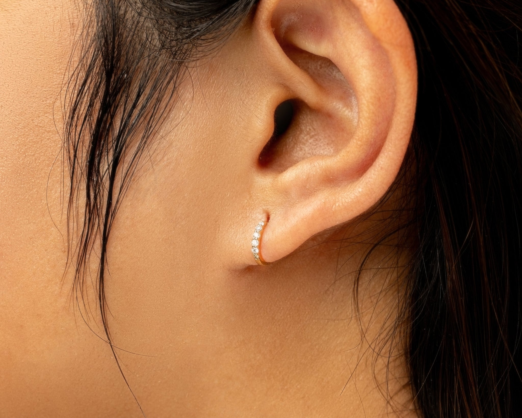 Close-up of an ear with a delicate diamond hoop earring