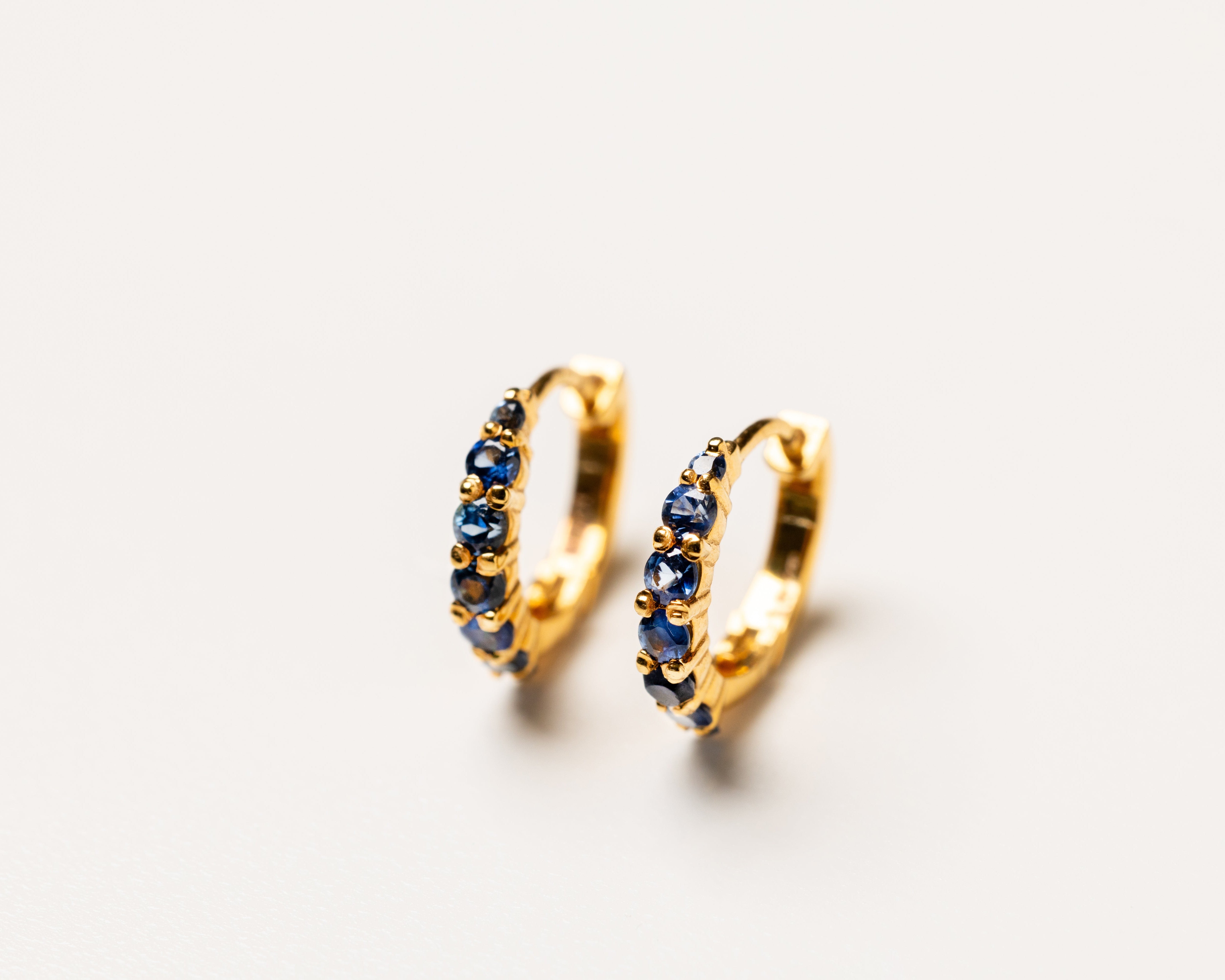 18k gold Gold hoop earrings with blue sapphire gemstones on a white background