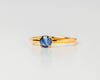 Gold ring with a blue sapphire gemstone on a light gray background