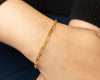 Gold bracelet on a wrist against a dark background
