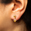 Close-up of an ear wearing a pair of yellow sapphire gemstone earrings.