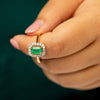 Close-up of a hand holding an emerald 18k solid gold ring with a green background