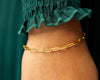 Gold bracelet on a person's wrist with a blurred green background