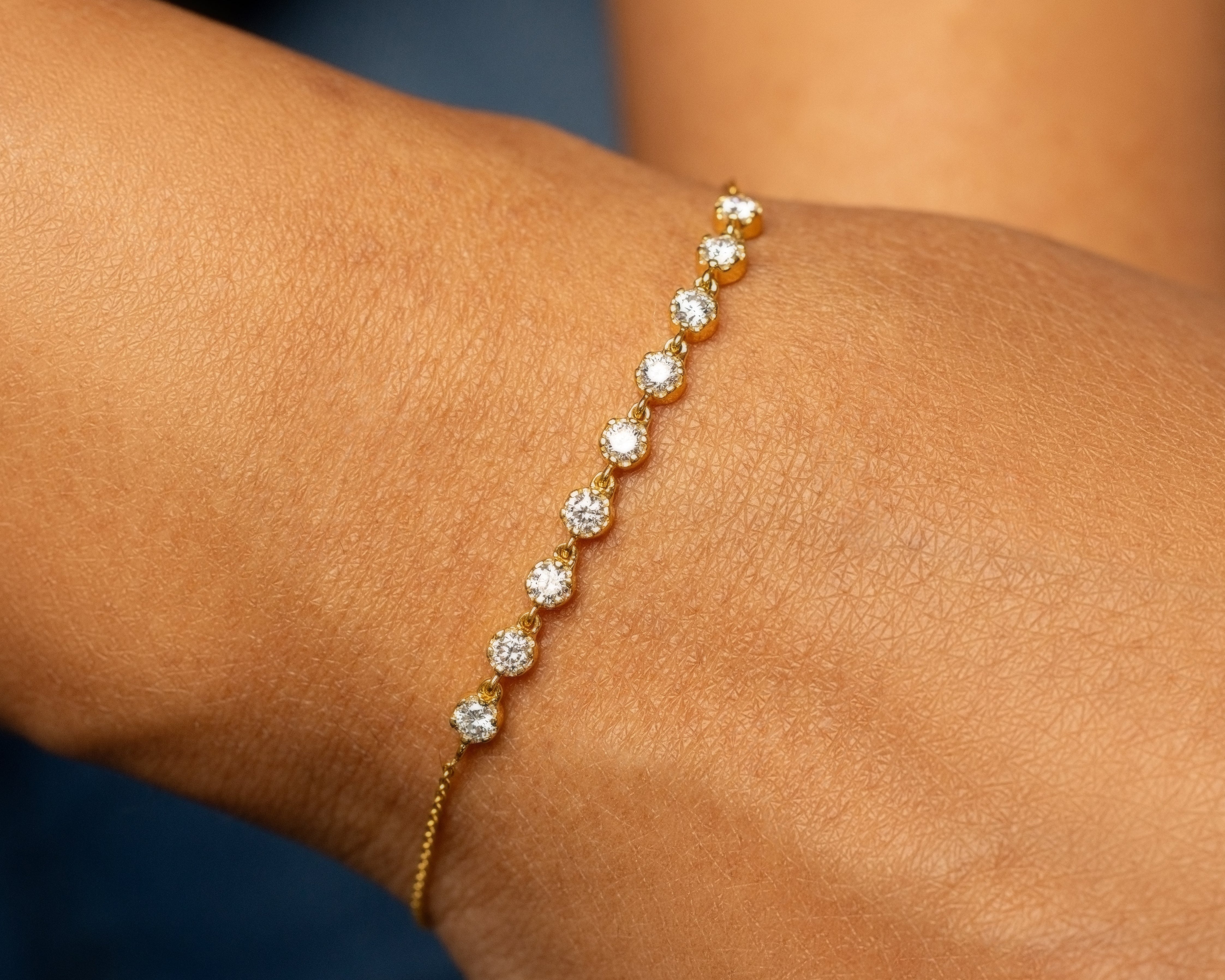 Gold bracelet with lab grown diamonds on a wrist against a blurred background