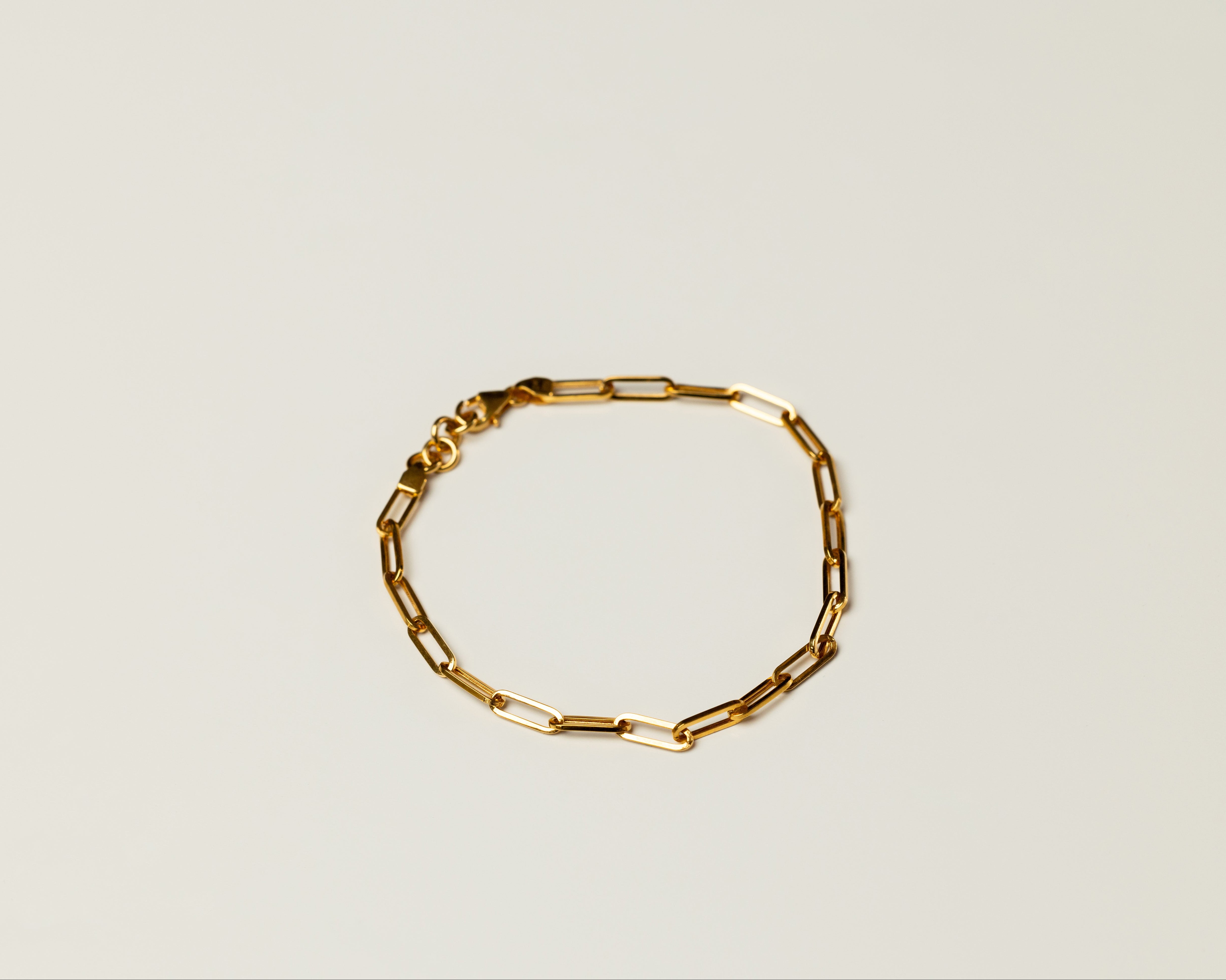Classic Gold chain link bracelet on a light beige background