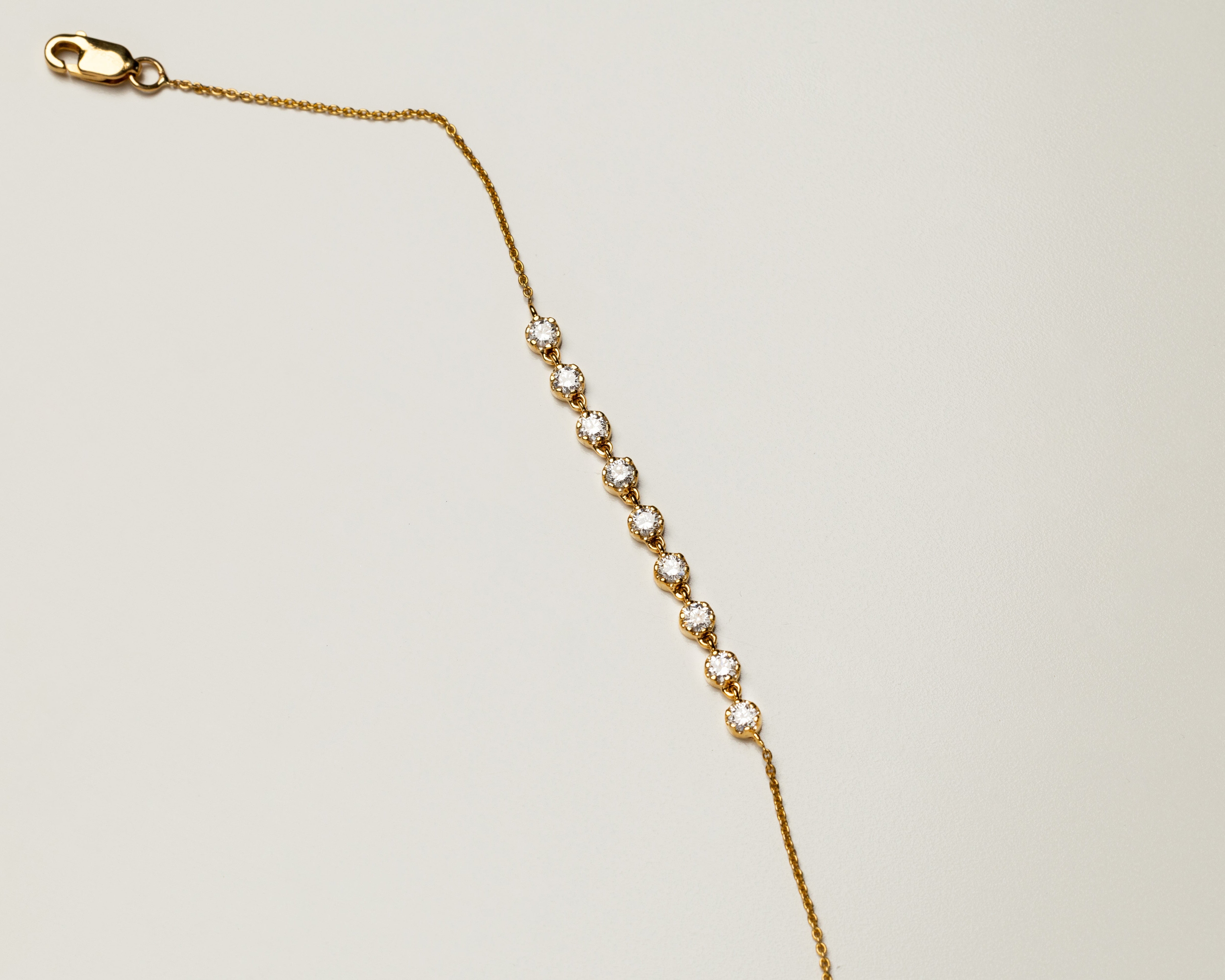 Gold chain bracelet with a lobster clasp on a light beige background