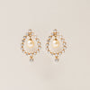 Pair of pearl earrings with gold accents on a beige background