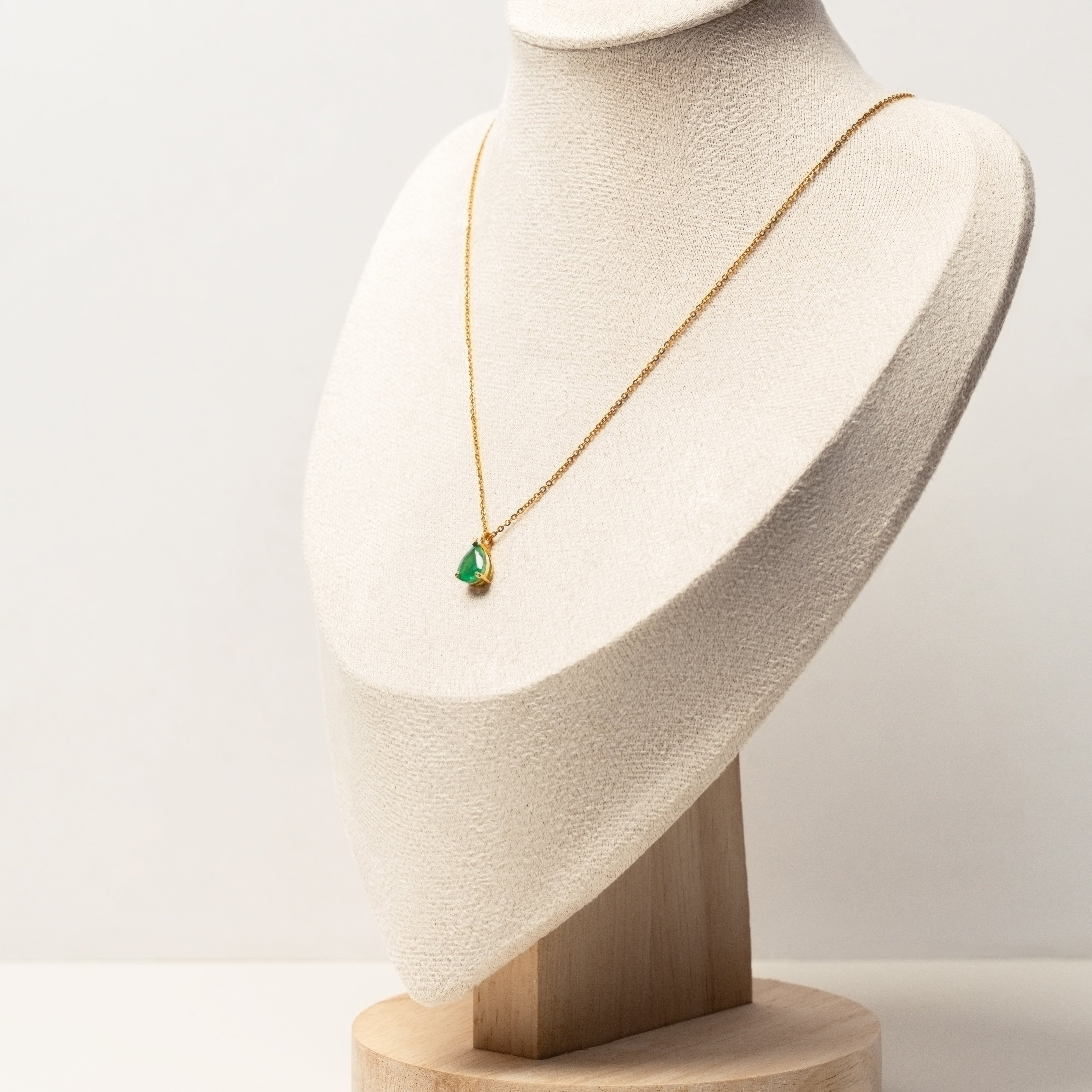 18k solid gold necklace with a green emerald pendant on a white mannequin bust against a white background
