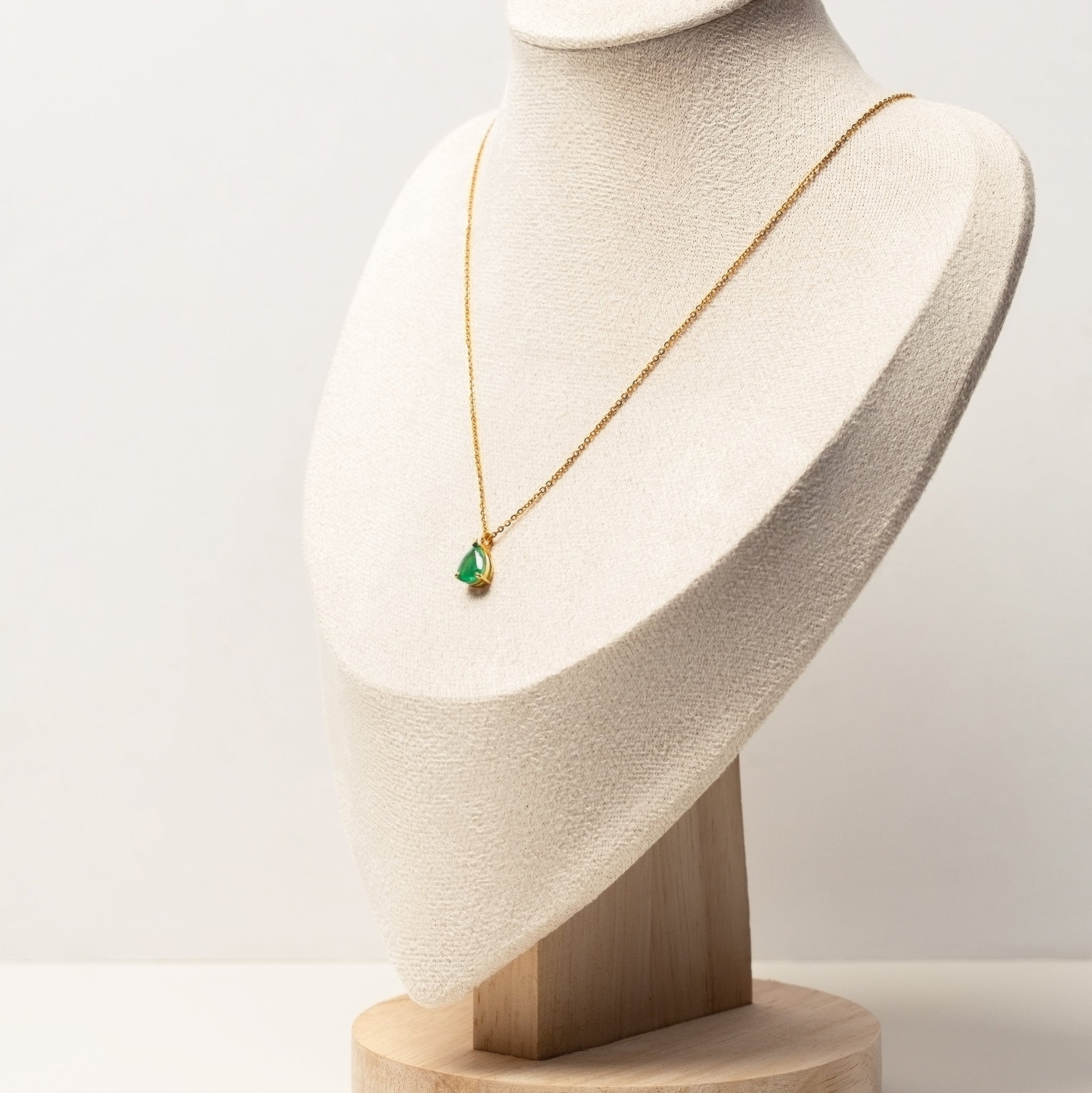 18k solid gold necklace with a green emerald pendant on a white mannequin bust against a white background