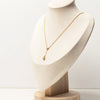 Gold necklace with a pendant on a mannequin bust with a plain background
