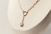Delicate necklace with a emerald cut diamond pendant on a neutral background