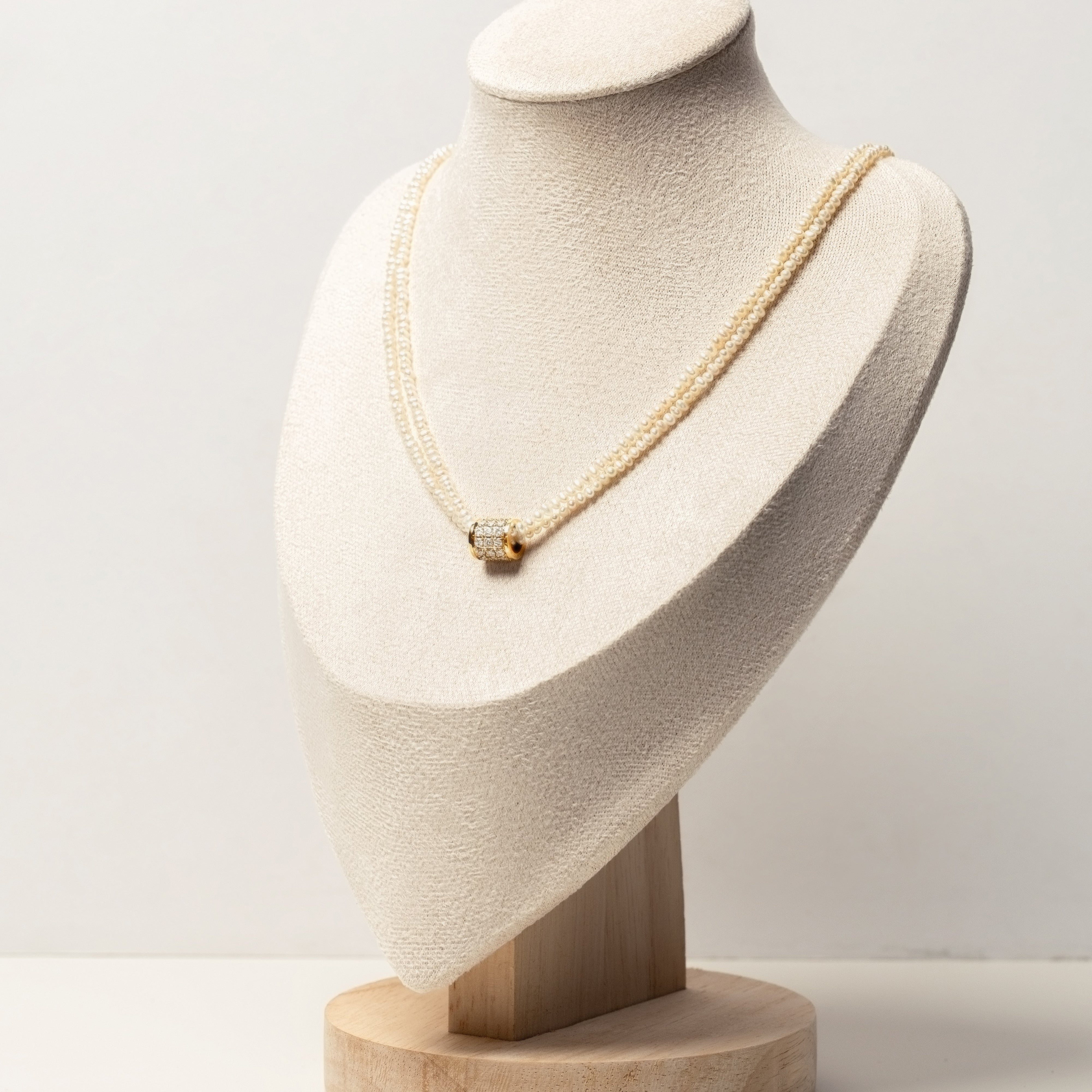 Classic pearl necklace on a mannequin bust with a plain background