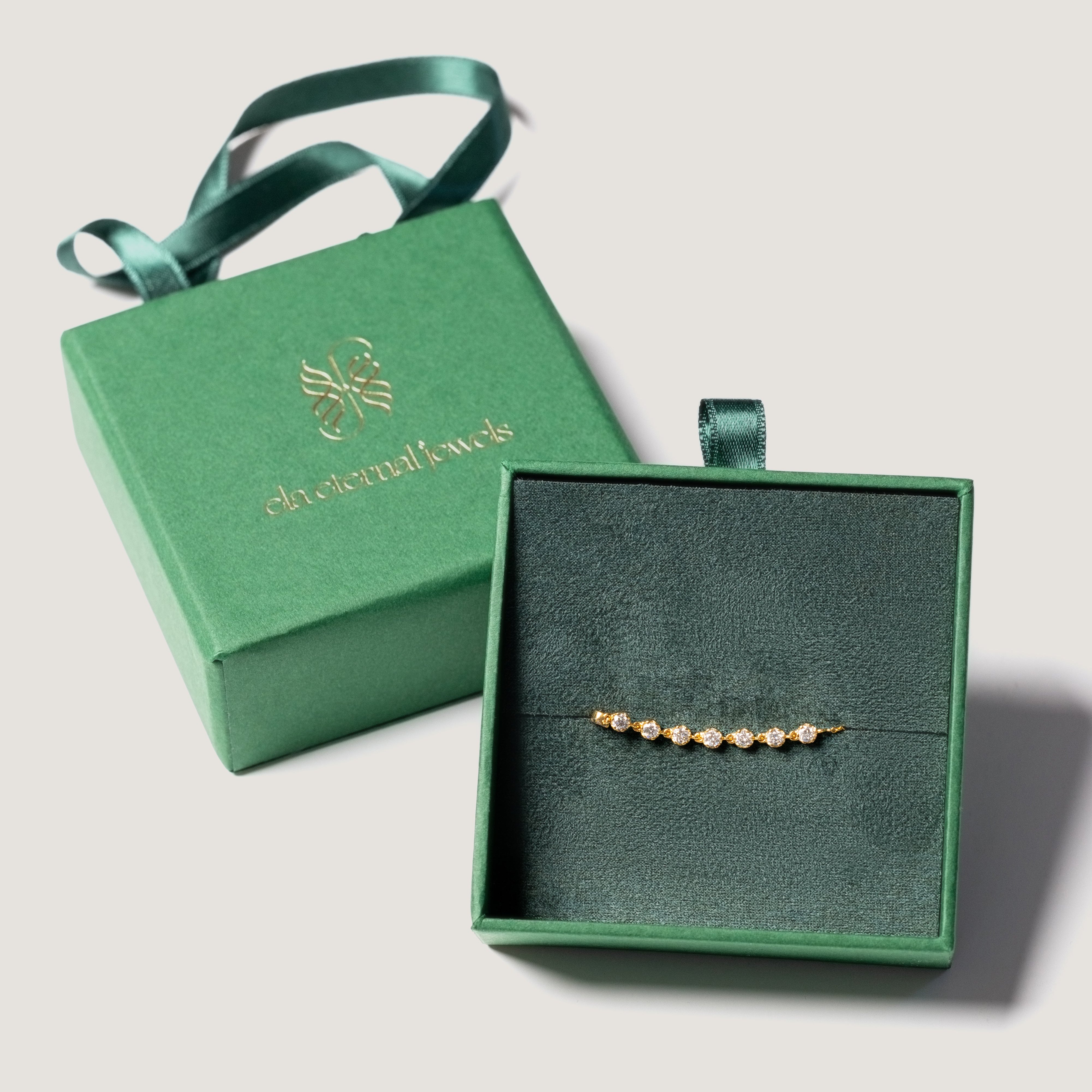 Green luxury jewelry box with a bracelet inside on a light gray background