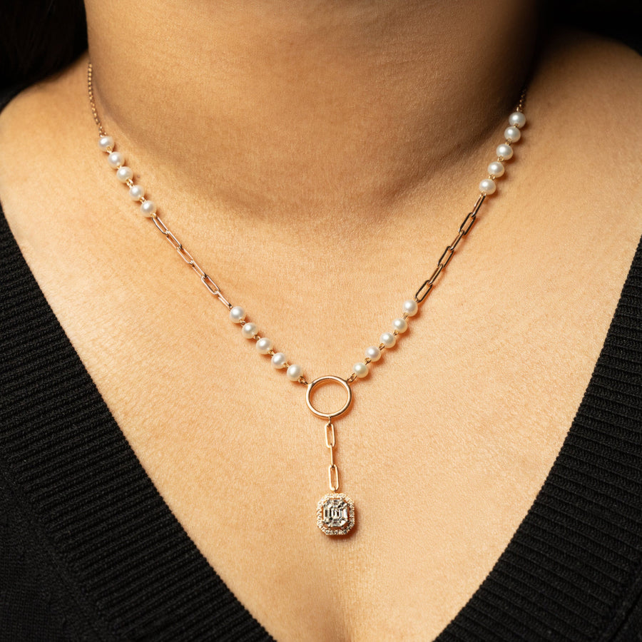 Pearl necklace with a diamond pendant worn by a person in a black top.
